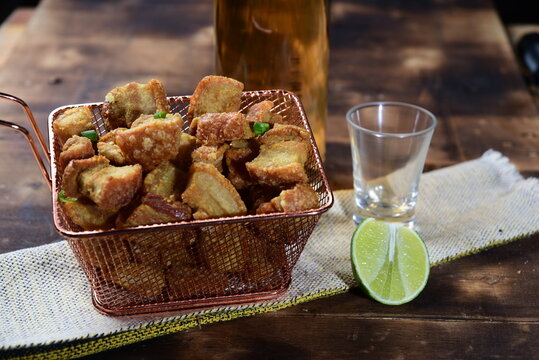 pork rinds (torresmo) fried in ceramic bowl on rustic wooden table in restaurant. typical dish of Brazilian and Asian cuisine panceta