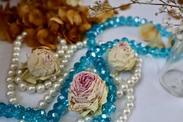 Fototapeta na wymiar White and blue beads with dried rose buds