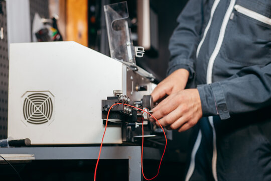 Hands of electrician working on cutting wires machine