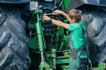 Young mechanic repair tractor outdoor - obrazy, fototapety, plakaty