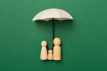 Umbrella and wooden family figures on color background, top view. Insurance coverage concept.