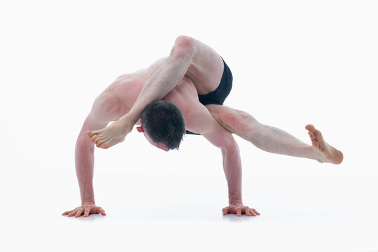 Eka pada sirsasana. (One Leg Behind the Head Pose), Ashtanga yoga  Man wearing sportswear doing Yoga exercise against white background. Horizontal image.