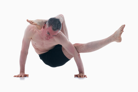 Eka pada sirsasana. (One Leg Behind the Head Pose), Ashtanga yoga  Side view of man wearing sportswear doing Yoga exercise against white background.
