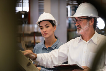 Factory manager inspecting industrial steel machinery and overseeing while supervising and...