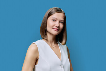 Portrait of young elegant business woman, on blue studio background