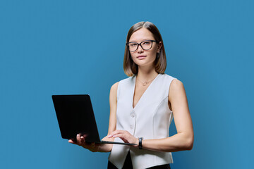 Serious young business woman with laptop on blue studio background