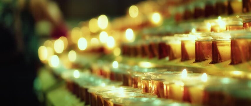 Many burning candles with blurred glowing background in the darkness.