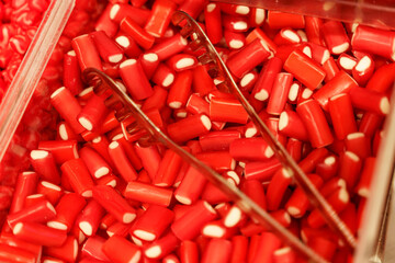 There are candies on the counter - red gummies and tongs.