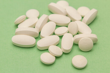 Fototapeta na wymiar Um conjunto de comprimidos brancos sobre uma superfície verde.