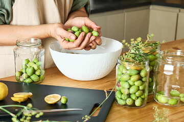 Woman preparing fermented olives in glass jar with slices of lemon, wild fennel and canning brine. Autumn vegetables canning. Healthy homemade food. Conservation of harvest.