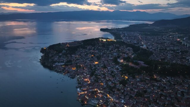 Aerial Twilight drone view of Ohrid City at Night in North Macedonia. Old Town on Ohrid lake with a beautiful fortress