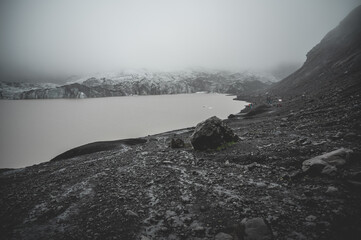 Solheimajokull Glacier, view from the distance during foggy weather, tourists hiking in the distance, wide angle shot, Iceland