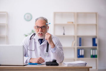 Old male doctor neurologist sitting in the clinic