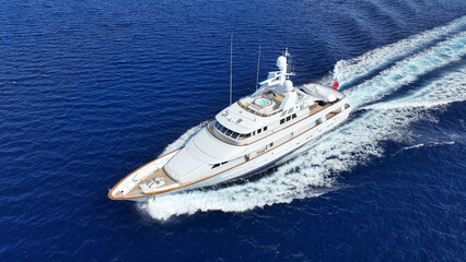 Aerial drone photo of latest technology mega yacht with wooden deck cruising deep blue...