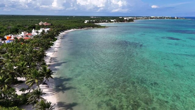 Drone view of coastline with blue Caribbean Sea and white sand beach with green forest on a cloudy day in Tulum 