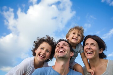 Young happy family with 2 kids smiling lookin up blue sky