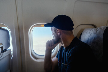 A pensive man sits at the window on an airplane.