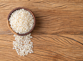Dried canjica, hominy or white corn on a bowl over wooden table with copy space