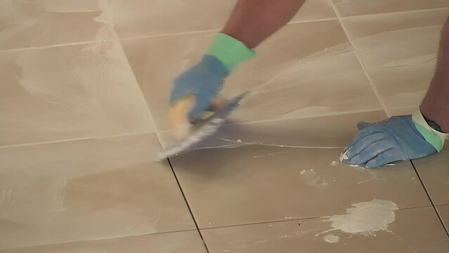 Bricklayer grouting the tiles of the floor