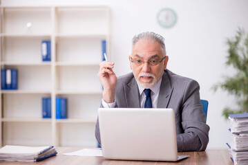 Old male employee working in the office