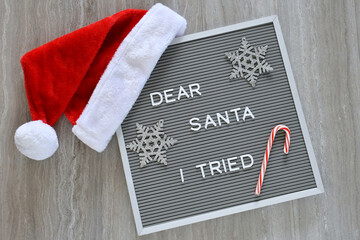 Dear Santa I Tried written on message board with Santa Claus hat, silver snowflakes candy cane