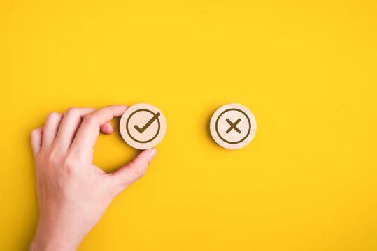 Hand choosing check mark sign, True and false symbols on wooden blocks, Accept and rejected for evaluation, Yes and no icons, Positive or negative decision, Making choice of approval or rejection