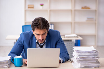 Young male employee and too much work in the office