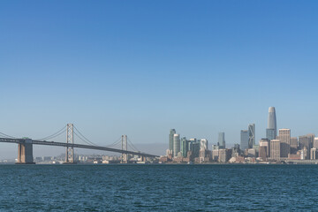 Fototapeta na wymiar A picturesque skyline of San Francisco Panorama at sunrise from Treasure Island, California, United States. Panoramic view of cityscape with mist and foggy air at morning day time.