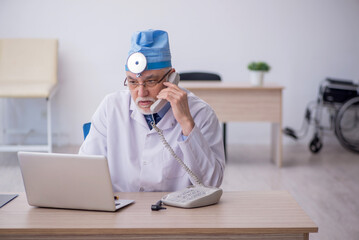 Old male docror otolaryngologist working in the clinic