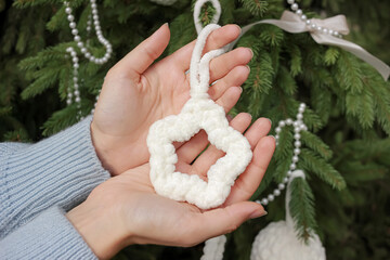 knitted fluffy star in the hands of a girl on background of a decorated Christmas tree. DIY handmade holiday toys decoration concept