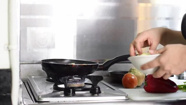 close-up of a latin woman's hands throwing plantains into a frying pan to fry them.