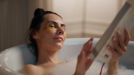 Carefree woman flipping book pages chilling bathroom. Rested lady reading novel