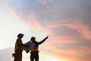 Two construction workers on a building site at sunset, Thailand