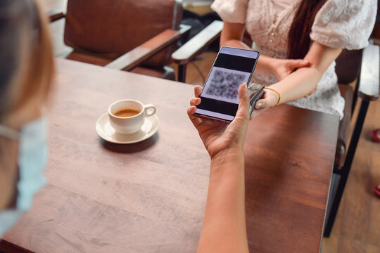 Woman scanning a QR code to make a payment in a coffee shop