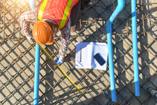 Overhead view of a construction worker measuring metal foundations on a building site, Thailand
