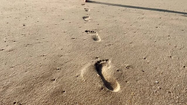 Footprints in the sand on the beach. The camera follows footprints of the teen child girl in a large sand dune on the beach. 4k resolution video