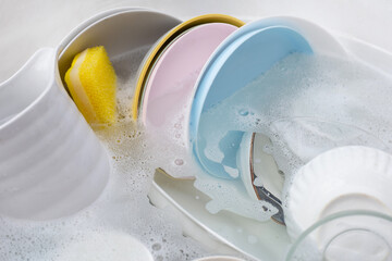 Dishes and bowls in water and bubbles of dishwashing liquid. Kitchen work