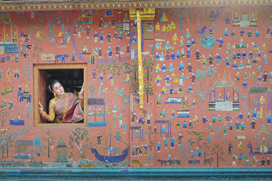 Woman looking out of an open temple window, Wat Xieng Thong, Luang Prabang, Laos