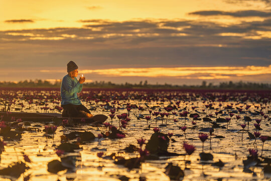 Fisherman sitting in a boat smoking a  cigarette at sunset, Red Lotus Sea (Talay Bua Daeng), Udon Thani, Thailand