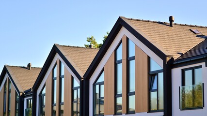 Suburban neighborhood with condominium complex. Suburban area with modern geometric family houses. Row of family houses against blue sky.