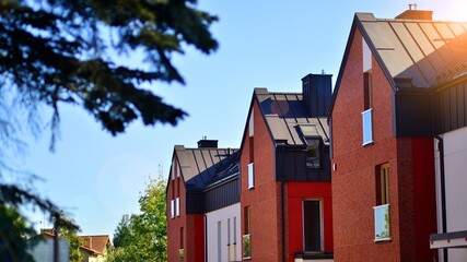 Suburban neighborhood with condominium complex. Suburban area with modern geometric family houses. Row of family houses against blue sky.