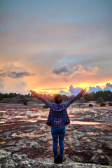 woman with arms up in front of landscape at sunset in rainny day, summer in the mountains 