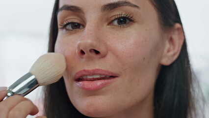 Portrait model applying powder home. Smiling woman putting blushes making makeup