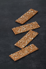 Buckwheat bread with sesame seeds and quinoa, in the form of thin strips, Dark gray background. Close-up