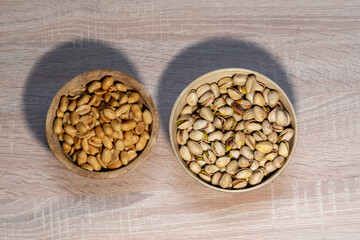 peanuts and pistachios on a wooden background in wooden bowls