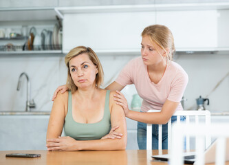 Teenage girl trying to talk and apologize to her offended mother after home disagreements.. - obrazy, fototapety, plakaty