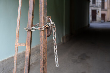 Padlock and chain on a metal gate in the arch of a house