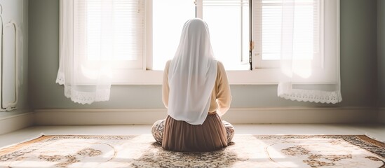 young muslim woman in hijab praying indoors near the window - obrazy, fototapety, plakaty