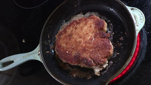 Pork chop frying in skillet or pan with heating element cycling on and off