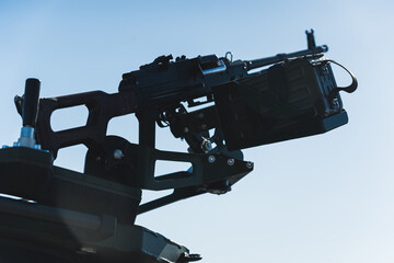 Closeup shot of medium machine gun against the background of sunny blue sky. Belt-fed machine gun. High quality photo - obrazy, fototapety, plakaty